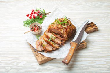 Baharat ve otlarla kavrulmuş hindi sarması. Bıçak ve ahşap beyaz arka plan manzaralı fırın kağıdı. Dilimler için pişirilmiş hindi fileto. Akşam yemeği için..