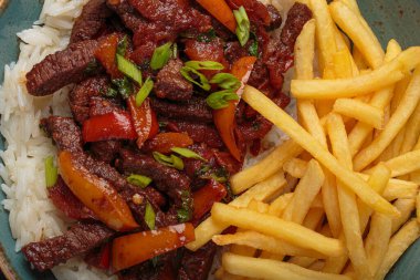 Patates kızartması, pirinç, kırmızı soğan ve domatesli sığır filetosundan yapılmış leziz Peru yemeği lomo saltado tabakta servis edilir.