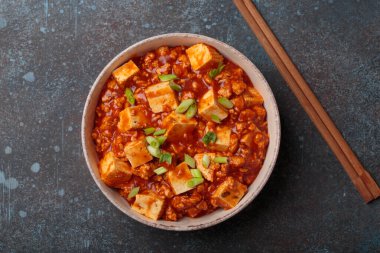 Mapo tofu, popüler bir Çin Sichuan yemeği, bir kasede servis edilir ve yeşil soğanla süslenir. Çubuklar kasenin yanında.