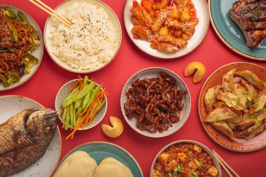 Variety of delicious chinese dishes on plates and bowls arranged on red background: kung pal chicken, sweet and sour pork, noodles, dumplings, mapo tofu, fish, rice, fortune cookies top view clipart