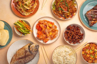 Tabaklardaki lezzetli Çin yemekleri ve tabaklar: kung pal tavuğu, tatlı ve ekşi domuz eti, erişte, hamur tatlısı, mapo tofu, balık, pirinç üstü görünümü