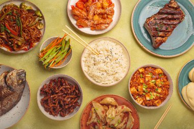 Tabaklarda çeşitli lezzetli Çin yemekleri ve yeşil arka planda sıralanmış kaseler: kung pal tavuğu, tatlı ve ekşi domuz eti, erişte, hamur tatlısı, mapo tofu, balık, pirinç üstü görünümü ve fotokopi alanı.