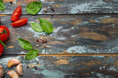 Kiraz domatesli yemek pişirme sınırı, taze yeşil fesleğen ve sarımsak karanfilleri kırsal renkli ahşap arka planda üst görünüm, yemek hazırlamak için malzemeler, kopyalama alanı.