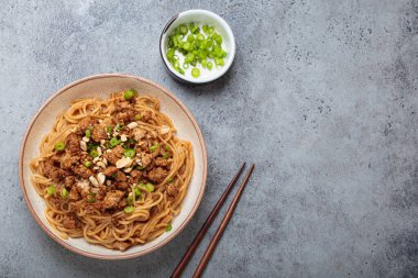 Dan Dan erişteleri yemek çubukları ve yeşil soğanla servis ediliyor. Sichuan mutfağının leziz lezzetlerini sergiliyorlar.