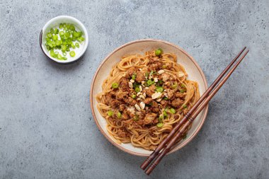 Dan Dan erişteleri yemek çubukları ve yeşil soğanla servis ediliyor. Sichuan mutfağının leziz lezzetlerini sergiliyorlar.