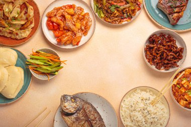 Variety of delicious chinese dishes on plates and bowls arranged on a table: kung pal chicken, sweet and sour pork, noodles, dumplings, mapo tofu, fish, rice top view with copy space clipart