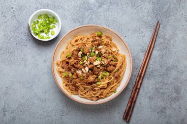 Dan Dan erişteleri yemek çubukları ve yeşil soğanla servis ediliyor. Sichuan mutfağının leziz lezzetlerini sergiliyorlar.