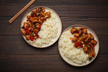 İki tabak Çin kung pao tavuğu, pilav, sebze ve baharatlı soslu fıstık. Ahşap arka planda üst manzara. Öğle veya akşam yemeği için mükemmel.