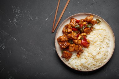 Çin usulü kung pao tavuğu pilav, sebze ve baharatlı soslu fıstık. Koyu arkaplanda üst görünüm. Öğle veya akşam yemeği için mükemmel, kopyalama alanı