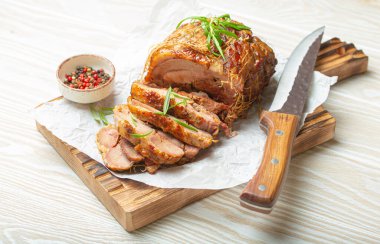 Baharat ve otlarla kavrulmuş hindi sarması. Bıçak ve ahşap beyaz arka plan manzaralı fırın kağıdı. Dilimler için pişirilmiş hindi fileto. Akşam yemeği için..