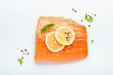 Taze çiğ somon balığı filetosu beyaz arka planda limon, kaba tuz ve yeşil otlarla izole edilmiş. Sağlıklı beslenme ve dengeli beslenme.