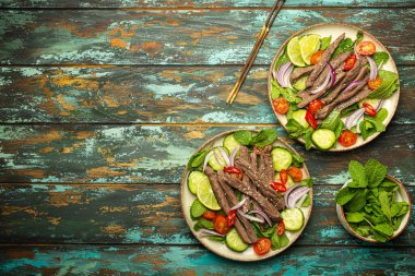 Geleneksel Tayland sığır eti salatası ve sebzeli ve nane arkaplanda servis edilen ahşap kaplama, sağlıklı egzotik Asya yemeği, yazı için yer.