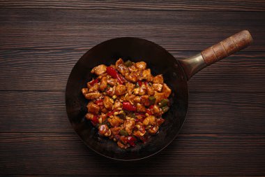 Çin kung pao tavuğu, tavuk, fıstık, sebze ve biberden yapılmış karıştırılmış bir tava, ahşap bir masada servis edilir.