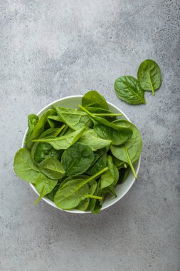 Taze ıspanak yaprakları gri bir arka planda, canlı yeşil renklerini ve sağlıklı cazibelerini sergiliyor, salatalar, meyve suları veya yan yemekler için mükemmel..