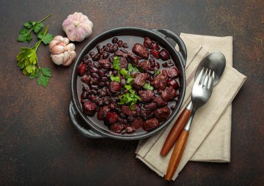 Brezilya feijoada 'sı, sağlıklı bir siyah fasulye güveci, çeşitli et kesimleri, ve sosis, taze maydanozla süslenmiş, kırsal döküm demir bir tencerede, servis edilmeye hazır.