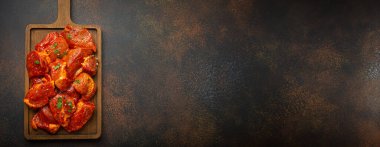 Çiğ doğranmamış domuz eti parçaları baharatlarla marine edilmiş ve tahta kesme tahtasının üzerinde maydanoz koyu kırsal arka planda. Salamura domuz filetosu ile yemek pişirmek. Metin için boşluk.