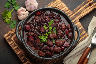 Brezilya feijoada 'sı, sağlıklı bir siyah fasulye güveci, çeşitli et kesimleri, ve sosis, taze maydanozla süslenmiş, kırsal döküm demir bir tencerede, servis edilmeye hazır.