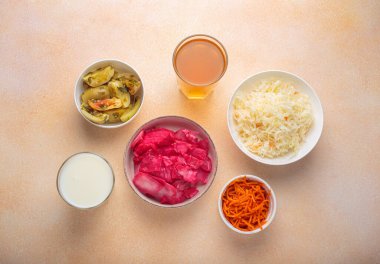 Sauerkraut, pickled cabbage, pickled cucumbers and tomatoes, fermented carrots, kefir and kombucha are arranged on a table, offering a variety of probiotic rich foods beneficial for gut health clipart