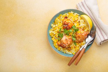 Lezzetli Hint usulü biryani tavuğu, taze kişniş ve limonla süslenmiş, bej bir masada fotokopi alanı olan bir kasede. Hindistan 'ın otantik yemeği