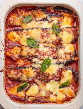 Klasik bir İtalyan yemeği olan parmesanlı patlıcan, patlıcan, domates sosu ve mozarella peyniri katmanları ile hazırlanır ve taze fesleğen yapraklarıyla süslenir.