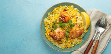 Lezzetli Hint usulü biryani tavuğu, taze kişniş ve limonla süslenmiş, mavi bir masada fotokopi alanı olan bir kasede. Hindistan 'ın otantik yemeği