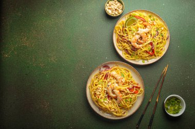 İki tabak Tayland eriştesi, karides, fıstık, limon, biber ve yeşil zemin üzerinde taze soğan ve yemek çubukları ve kabın içindeki malzemelerle. Geleneksel Tayland yemeği, metin için alan