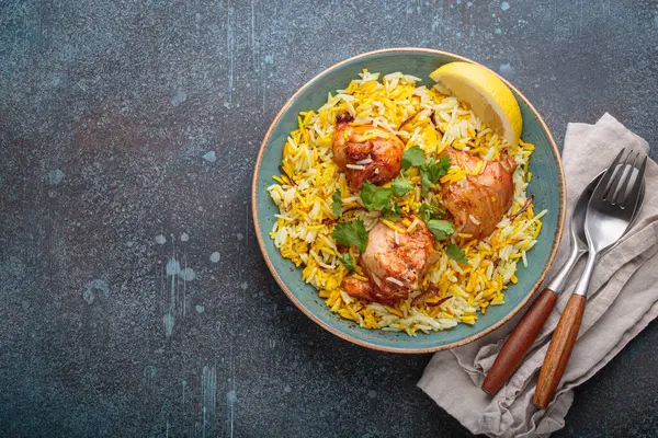 Lezzetli Hint usulü biryani tavuğu, taze kişniş ve limonla süslenmiş, fotokopi alanı olan bir kırsal masada. Hindistan 'ın otantik yemeği