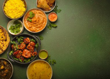 Yeşil bir masadaki çeşitli Hint yemeklerinin genel görünümü, köri, tandır tavuğu, tavuk tikka masala, dal, Palak paneer, paratha, pilav, samosa gibi. Hindistan mutfağı, kopyalama alanı