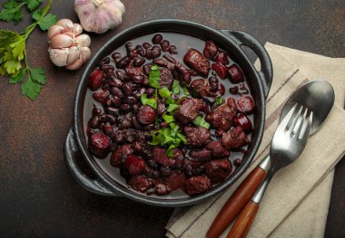 Brezilya feijoada 'sı, sağlıklı bir siyah fasulye güveci, çeşitli et kesimleri, ve sosis, taze maydanozla süslenmiş, kırsal döküm demir bir tencerede, servis edilmeye hazır.
