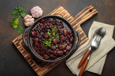 Brezilya feijoada 'sı, sağlıklı bir siyah fasulye güveci, çeşitli et kesimleri, ve sosis, taze maydanozla süslenmiş, kırsal döküm demir bir tencerede, servis edilmeye hazır.