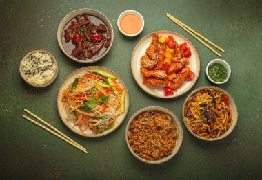 Çeşitli Çin yemekleri, tatlı ve ekşi tavuk, soslu sığır eti, erişte, kızarmış pirinç, salata ve ahşap çubuklar. Çin ya da Asya restoranı konsepti