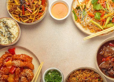 Çeşitli Çin yemekleri, tatlı ve ekşi tavuk, soslu sığır eti, erişte, kızarmış pirinç, salata ve ahşap çubuklar merkezi boş bir alanda çerçeve oluşturuyorlar. Boşluğu kopyala