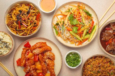 Çeşitli Çin yemekleri, tatlı ve ekşi tavuk, soslu sığır eti, erişte, kızarmış pirinç, salata ve ahşap çubuklar. Çin ya da Asya restoranı konsepti