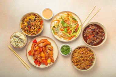 Çeşitli Çin yemekleri, tatlı ve ekşi tavuk, soslu sığır eti, erişte, kızarmış pirinç, salata ve ahşap çubuklar. Çin ya da Asya restoranı konsepti