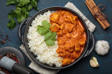 Hintli tavuk tikka masala kremalı domates soslu, basmati pilavı, taze kişniş ve baharatla servis ediliyor, geleneksel Hint yemeği.