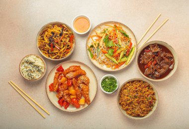 Çeşitli Çin yemekleri, tatlı ve ekşi tavuk, soslu sığır eti, erişte, kızarmış pirinç, salata ve ahşap çubuklar. Çin ya da Asya restoranı konsepti