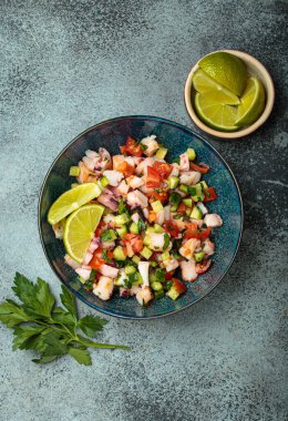 Taze ve canlı Peru deniz ürünleri ceviche ile karides, ahtapot, domates, salatalık ve maydanoz, yukarıdaki taştan bir arka planda limonla servis edilmiş, Peru yemeği.