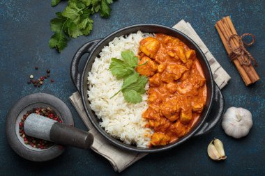 Hintli tavuk tikka masala kremalı domates soslu, basmati pilavı, taze kişniş ve baharatla servis ediliyor, geleneksel Hint yemeği.