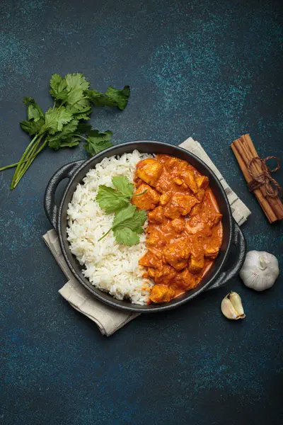 Hintli tavuk tikka masala kremalı domates soslu, basmati pilavı, taze kişniş ve baharatla servis ediliyor, geleneksel Hint yemeği.