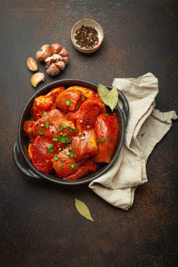 Çiğ doğranmamış et parçaları baharatlarla marine edilmiş ve siyah güveçte maydanoz koyu kırsal arka planda üst manzara. Baharatlı et fileto ile yahni pişiriyorum..