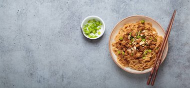 Dan Dan erişteleri yemek çubukları ve yeşil soğanla servis ediliyor. Sichuan mutfağının leziz lezzetlerini sergiliyorlar.
