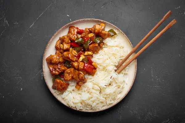 Çin usulü kung pao tavuğu pilav, sebze ve baharatlı soslu fıstık. Koyu arkaplanda üst görünüm. Öğle veya akşam yemeği için mükemmel.