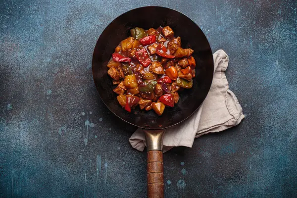 Renkli çan biberleri ve ananas parçalarıyla tavada tatlı ve ekşi domuz eti, klasik Asya yemeği.