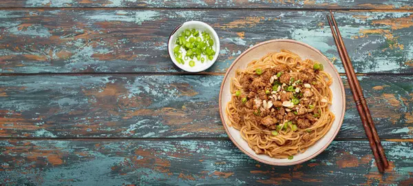 Dan Dan eriştesi fıstıklı ve yeşil soğanlı. Çubuklu. Sichuan mutfağında servis ediliyor.