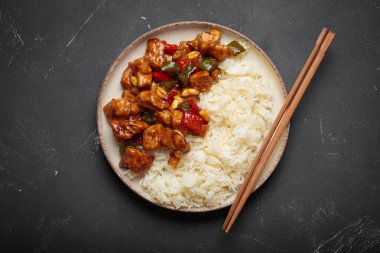 Çin usulü kung pao tavuğu pilav, sebze ve baharatlı soslu fıstık. Koyu arkaplanda üst görünüm. Öğle veya akşam yemeği için mükemmel.