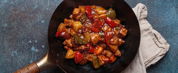 Renkli çan biberleri ve ananas parçalarıyla tavada tatlı ve ekşi domuz eti, klasik Asya yemeği.