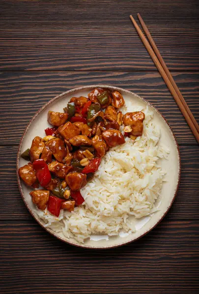 Çin usulü kung pao tavuğu pilav, sebze ve baharatlı soslu fıstık. Ahşap arka planda üst manzara. Öğle veya akşam yemeği için mükemmel.