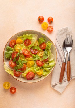 Taze yeşil marullu ızgara somon filetosu, renkli vişneli domates, salata üstü, bej renkli pastel arka plan, sağlıklı beslenme alışkanlıkları.