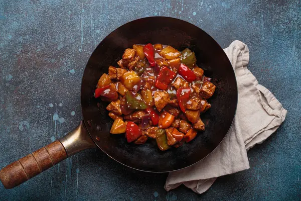 Renkli çan biberleri ve ananas parçalarıyla tavada tatlı ve ekşi domuz eti, klasik Asya yemeği.