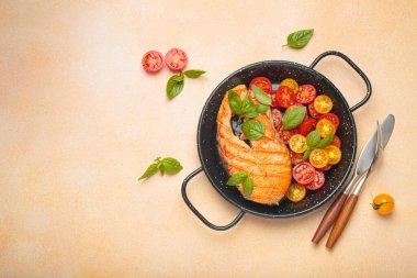 Siyah tavada ızgara somon bifteği, yanında canlı vişne domatesleri ve taze fesleğen yaprakları, sağlıklı beslenme ya da diyet konsepti, kopyalama alanı.